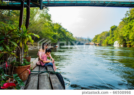 Mother and son sit to feed the fish 66508998