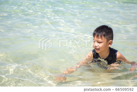 Portrait of Asian boy wearing black shirt sitting in the sea. Portrait of Asian boy wearing black shirt sitting in the sea. 66509592