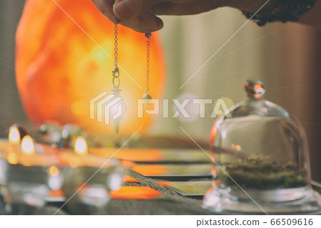 Hand with pendulum over tarot cards 66509616