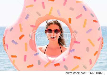 Beautiful young woman is posing with a doughnut Beautiful young woman is posing with a doughnut 66510029