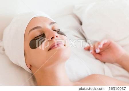 Young woman with closed eyes and black eye patches Young woman with closed eyes and black eye patches 66510087