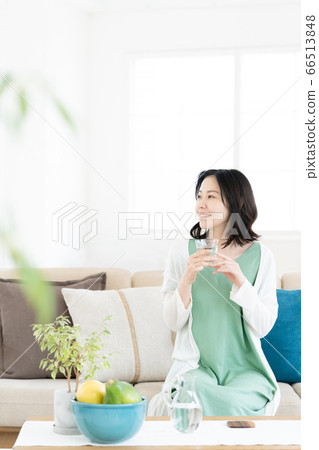 Middle woman drinking a glass of water in the living room 66513848