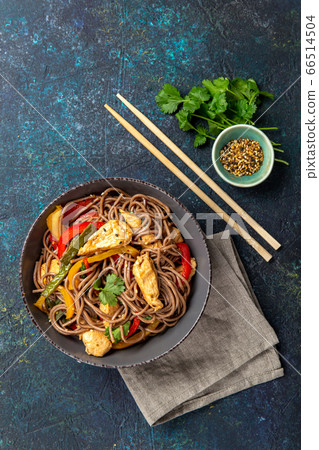 Japanese dish buckwheat soba noodles with chicken and vegetables carrot, bell pepper and green beans in grey bowl, top view, copy space 66514504