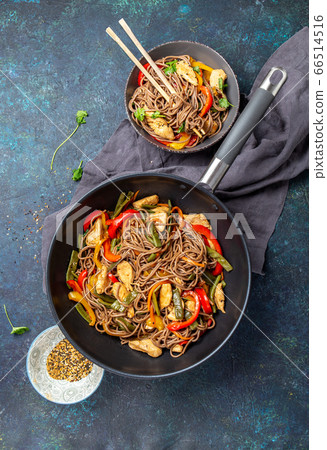 Japanese dish buckwheat soba noodles with chicken and vegetables carrot, bell pepper and green beans in wok on dark blue background Japanese dish buckwheat soba noodles with chicken and vegetables carrot, bell pepper and green beans in wok on dark blue background 66514516