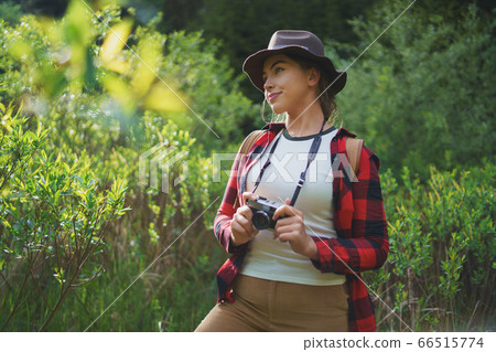Young woman with camera on a walk in forest in summer nature, standing. Young woman with camera on a walk in forest in summer nature, standing. 66515774