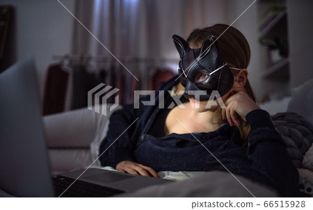 Young girl with cat mask and laptop indoors online dating and abuse concept. Young girl with cat mask and laptop indoors online dating and abuse concept. 66515928