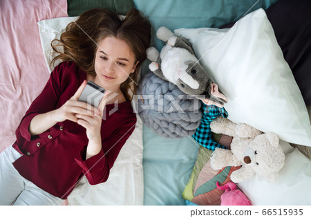 Top view of happy young girl smiling and taking selfie on bed, online dating concept. Top view of happy young girl smiling and taking selfie on bed, online dating concept. 66515935