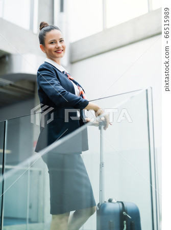 Portrait of attractive flight attendant standing on airport, looking at camera. 66515989