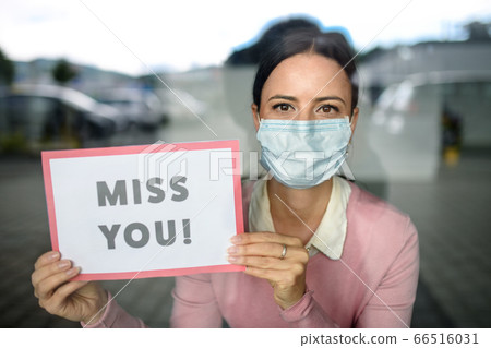 Portrait of teacher with face mask after lockdown, holding miss you sign. 66516031