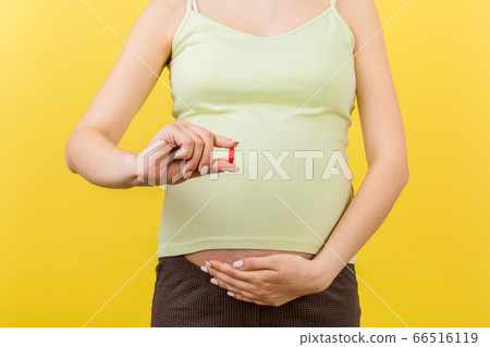 Close up of a pill in pregnant woman hand's at 66516119
