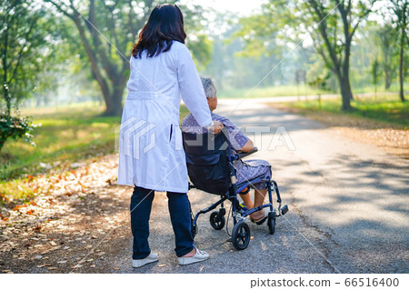 Doctor help and care Asian senior woman patient sitting on wheelchair at park in nursing hospital 66516400
