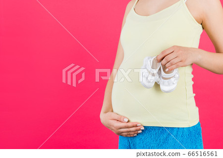 Close up of pregnant woman holding a pair of shoes 66516561