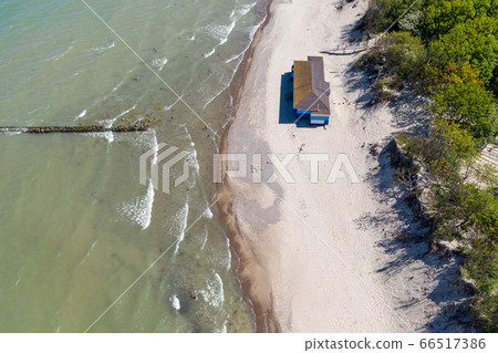 A lonely house standing on a sandy beach between the forest and the sea. Removed from the top of the drone. 66517386