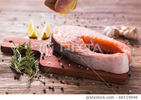 Squeezing fresh lemon juice on the fillets of fish. Cooking salmon steak. Squeezing fresh lemon juice on the fillets of fish. Cooking salmon steak. 66519946