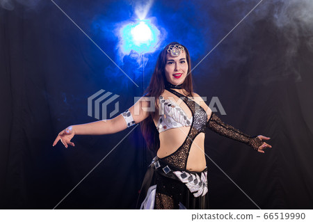 Young woman belly dancer in exotic dress with gold, dancing tribal fusion dance in studio. 66519990