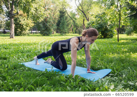 Beautiful woman doing Pilates in the green park Beautiful woman doing Pilates in the green park 66520599