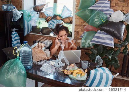Unkempt young Asian woman having phone conversation at her cluttered flat 66521744