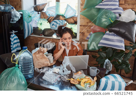Slatternly Asian woman spending time indoors among piles of garbage 66521745