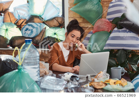 Concentrated young female working distantly at home surrounded by garbage 66521969