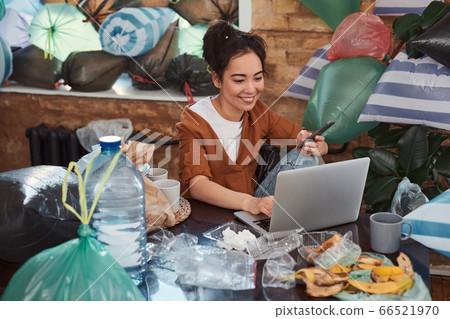 Young female using computer and smartphone in a messy room 66521970