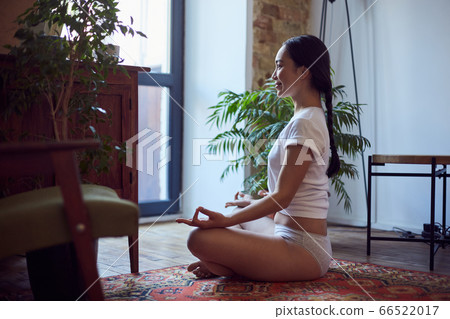 Smiling asian female meditating at home in the morning 66522017