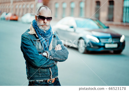 old modern man walks in the street, on the background of street and cars 66523178