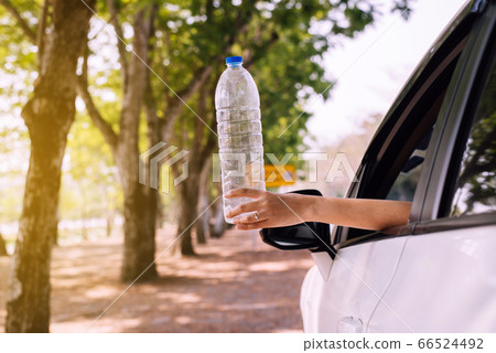 Woman hand holding plastic bottle on the road,Global warming environmental protection concept 66524492