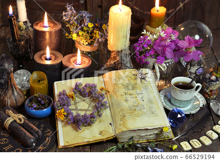 Open witch book with spells, black candles and cup of coffee. Esoteric, wicca and occult background with magic objects, fortune telling and divination ritual, Halloween mystic background.  66529194