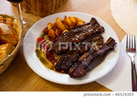 Tasty beef steak on the bone with potatoes served at plate, spanish dish Tasty beef steak on the bone with potatoes served at plate, spanish dish 66529303