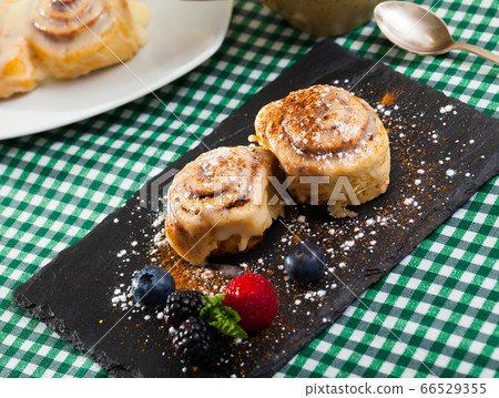 Tasty baked cinnabon rolls served with powdered sugar and berries Tasty baked cinnabon rolls served with powdered sugar and berries 66529355