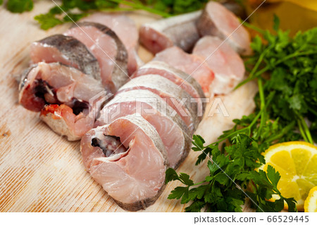 Raw sea merlang with lemon and parsley on cutting board 66529445