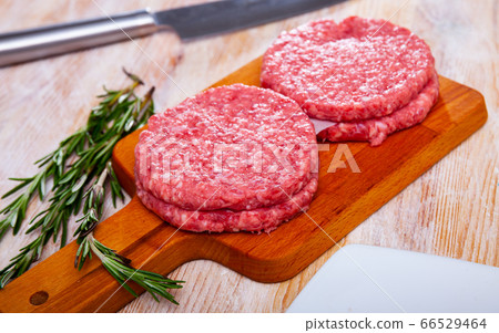 Close up of raw burger cutlet from pork on wooden table Close up of raw burger cutlet from pork on wooden table 66529464
