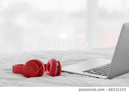 Red modern headphones and laptop computer on white bedsheet. Red modern headphones and laptop computer on white bedsheet. 66532133