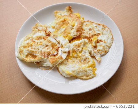 Fried eggs on a white porcelain plate Fried eggs on a white porcelain plate 66533221
