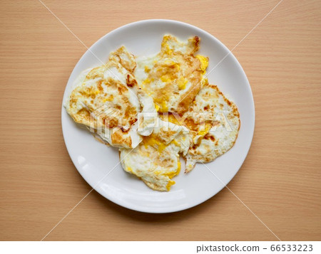 Fried eggs on a white porcelain plate Fried eggs on a white porcelain plate 66533223