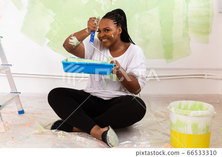 Funny Afro american woman painting an apartment. Renovation, repair and redecoration concept. Funny Afro american woman painting an apartment. Renovation, repair and redecoration concept. 66533310