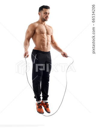 Shirtless bodybuilder jumping using rope. Shirtless bodybuilder jumping using rope. 66534206
