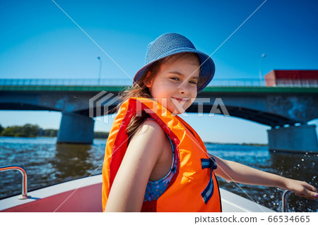 little girl in a swimming vest sits in a motorboat  66534665