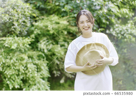 Young woman with straw hat in the garden [image of summer] 66535980