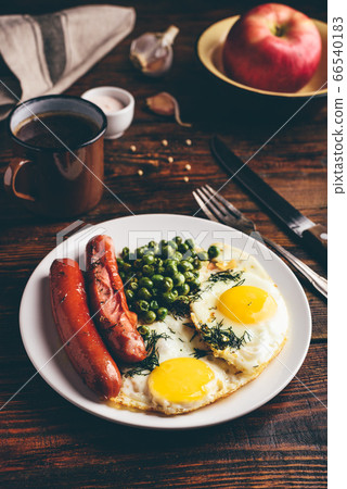 Breakfast with fried eggs, sausages and green peas 66540183