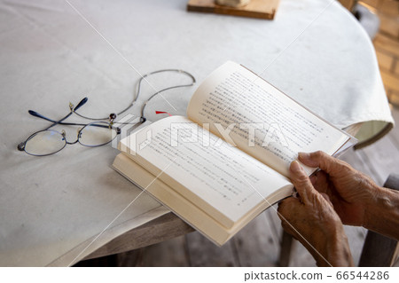 Elderly woman trying to read with reading glasses 66544286