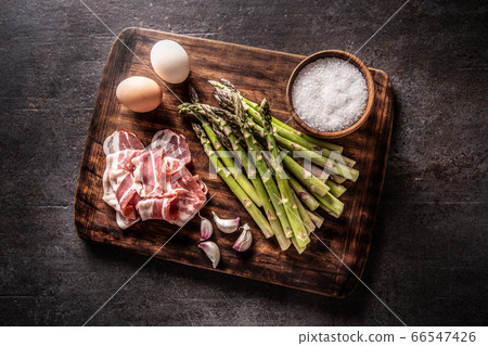 Asparagus eggs bacon and garlic on butcher board 66547426