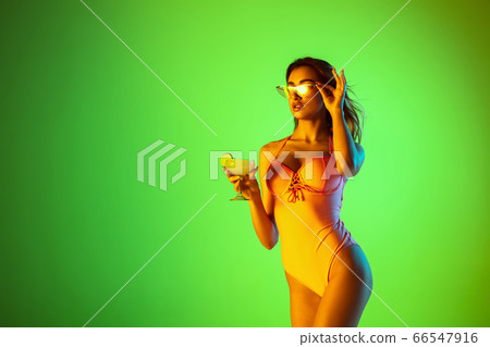 Beautiful girl in fashionable swimsuit isolated on gradient studio background in neon light. Summer, resort, fashion and weekend concept Beautiful girl in fashionable swimsuit isolated on gradient studio background in neon light. Summer, resort, fashion and weekend concept 66547916