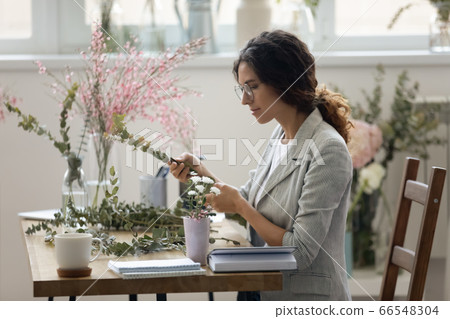 Young female florist compose floral decorations or bouquets Young female florist compose floral decorations or bouquets 66548304
