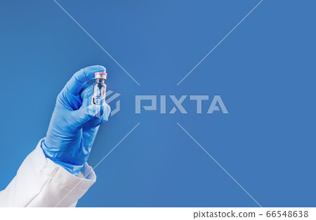 Medicine or vaccine vial in a hand of a doctor on blue Medicine or vaccine vial in a hand of a doctor on blue 66548638