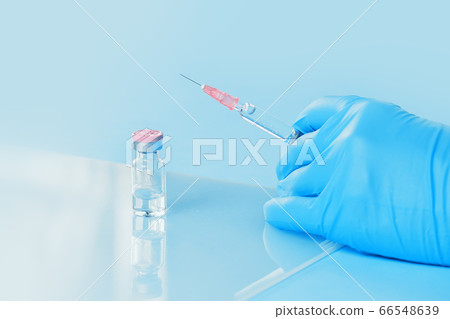 Syringe in a hand and vaccine on blue Syringe in a hand and vaccine on blue 66548639