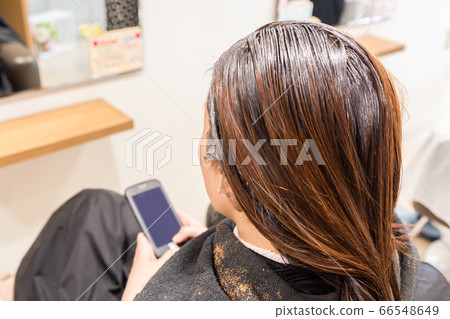 一個女人在一家美容院著色時消磨時間 一個女人在一家美容院著色時消磨時間 66548649