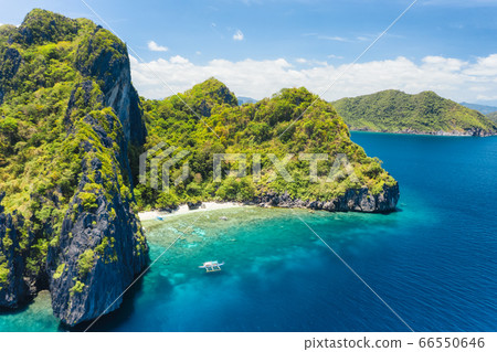Aerial drone view of tropical beach with lonely boat on Entalula Island. Karst limestone formation mountain surrounded by blue ocean and beautiful coral reef 66550646