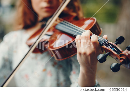 Beautiful girl in a summer park with a violin 66550914