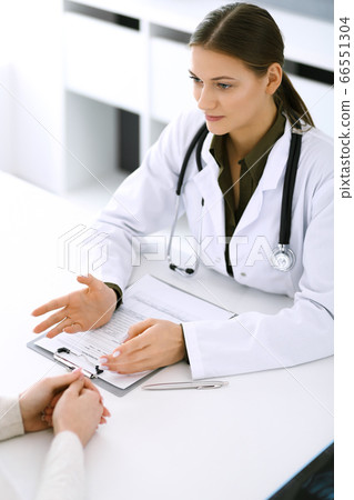 Woman doctor reassuring her female patient at hospital office. Medical ethics, human support and trust concept in healthcare 66551304